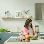 A woman blends fresh ingredients for a healthy smoothie in a stylish kitchen, promoting wellness.